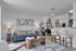 Contemporary open-plan living space featuring stylish furniture, a cozy blue sofa with accent pillows, modern artwork, and a sleek breakfast bar with elegant seating.