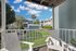 Charming balcony view showcasing serene landscaped courtyard with cozy seating, vibrant greenery, and picturesque sky.