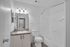 Modern bathroom with a granite countertop, sleek fixtures, and efficient in-unit laundry.