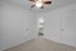 Inviting bedroom with plush carpet, modern ceiling fan, and a view into an elegant bathroom with granite countertop.