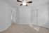 Inviting bedroom with plush carpet, modern ceiling fan, and spacious closet with sliding doors.