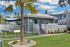 Charming apartment complex with a modern exterior, lush landscaping, and an inviting outdoor fitness area under palm trees.