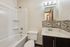 Modern bathroom with sleek tile accents, marble countertop, and a pristine white bathtub.