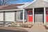 Charming apartment exterior with bold red doors and attached garage under a clear blue sky.