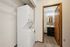 Chic apartment corner featuring an efficient stackable washer and dryer setup next to a modern bathroom with sleek vanity and contemporary backsplash.