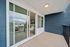 Inviting balcony with a fresh blue wall, featuring modern sliding glass doors opening to a bright living space, perfect for relaxing outdoors.