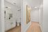 Inviting hallway with elegant wood flooring, vibrant artwork, and a modern bathroom featuring sleek cabinetry and stylish fixtures.