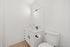 Modern bathroom with sleek white vanity, elegant black fixtures, large mirror, and inviting wood flooring.