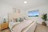 Bright and airy bedroom with modern decor, featuring a cozy bed, stylish artwork, and a large window with a serene scenic view.