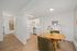 Modern dining area adjacent to a sleek white kitchen, featuring stylish decor and bright, airy ambiance.