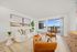 Bright and inviting living room with modern decor, featuring a cozy white sofa, stylish wooden coffee table, and stunning views through large sliding doors.