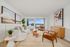 Chic and inviting living room with modern decor, featuring cozy seating, elegant artwork, and a scenic balcony view. Perfect blend of comfort and style.