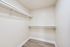 Spacious walk-in closet featuring sleek shelving and modern hardwood flooring, ideal for organized living.