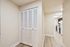 Bright hallway leading to a modern kitchen with sleek black cabinets and appliances, enhancing a contemporary living space.