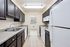 Modern galley kitchen with sleek dark cabinets, stainless steel sink, and bright natural lighting.