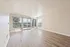 Bright and spacious living room with modern wood flooring, large windows, and sliding glass doors opening to a scenic balcony view.