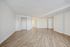 Spacious open-concept room with elegant wooden flooring and bright natural light, perfect for modern living.