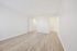Bright and airy room with sleek wood flooring and open closet, ideal for modern living.