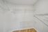 Spacious walk-in closet with elegant wooden flooring and ample shelving for optimal storage.