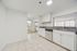 Bright and modern kitchen with sleek granite countertops, stainless steel appliances, and open layout extending to a sunlit living area.