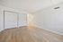 Bright and spacious bedroom with sleek hardwood floors, dual closets, and modern white walls for a minimalist appeal.