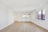 Bright, spacious open-plan living area with sleek hardwood floors and a large window offering natural light and modern kitchen view.