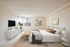 Elegant bedroom with plush bedding, stylish decor, and abundant natural light from a large window.