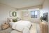 Elegant bedroom with plush bedding, chic decor, and a window offering stunning city views.