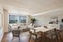 Elegant living room with a large window view, modern sectional sofa, chic marble-top dining table, and stylish decor.