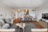 Modern open-plan living room with cozy seating, stylish decor, and a view of a sleek kitchen and dining area.