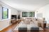 Bright, spacious living room featuring a modern sectional sofa, chic decor, and expansive windows with lush green views.