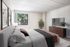 Inviting bedroom with a spacious layout, natural light streaming through the window, elegant king-size bed, and a stylish entertainment console.