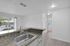 Bright and modern apartment kitchen with granite countertops, sleek sink, and a view of palm trees through large windows.
