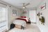 Inviting bedroom with modern decor, featuring a cozy bed with red accents, stylish wall art, and ample natural light through large windows.
