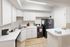 Modern kitchen with sleek white cabinets, elegant marble countertops, and stainless-steel appliances, creating a stylish and inviting cooking space.