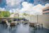 Charming outdoor space with stylish wicker seating and modern grills, perfect for entertaining under a blue sky.