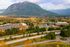 Scenic aerial view showcasing a vibrant town nestled against a majestic mountain backdrop with lush greenery and autumn foliage.