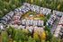 Charming aerial view of colorful townhouses nestled in a lush green forest, featuring a vibrant community garden and playground at the center.