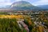 Scenic aerial view showcasing a vibrant community nestled among lush forests, with majestic mountains in the background and the charm of autumn foliage enhancing the landscape.