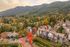 Charming hillside neighborhood with cozy homes nestled amidst lush greenery and vibrant autumn foliage, offering serene mountain views.