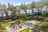 Charming mountainside townhouse community featuring lush greenery, a vibrant playground, and inviting outdoor seating areas for relaxation.