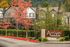 Charming apartment complex surrounded by vibrant autumn leaves and lush greenery, with elegant architecture and welcoming signage.