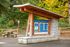 Entrance to Tennant Trailhead Park featuring an informative wooden sign with lush green forest backdrop, inviting nature exploration.