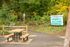 Charming forest trail entry at Tennant Trailhead Park featuring a cozy picnic table surrounded by lush greenery and vibrant autumn foliage.