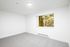 Bright and airy room with fresh white walls, plush gray carpet, and large window overlooking lush greenery.