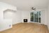 Bright living room with modern fireplace, wooden floors, and scenic glass doors opening to a serene balcony view.