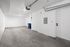 Spacious modern garage with minimalist design, featuring pristine white walls and gray concrete flooring.