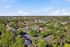 Townhomes at TSC Bird's-eye view of a lush, tranquil residential community with a sparkling central pool, surrounded by charming homes and verdant trees under a bright blue sky.
