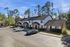 Townhomes at TSC Inviting townhouse complex with charming white facades, surrounded by lush greenery and ample parking space under a clear blue sky.