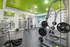 Townhomes at TSC Modern gym with vibrant green ceiling, featuring diverse weightlifting equipment and mirrors for a comprehensive workout experience.